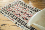 Faded cochineal red, ivory, and black guls with diamond motifs on distressed Turkish Kilim.