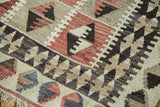 Distressed Kilim rug with reciprocating guls, diamond motifs, faded colors, and fringe.
