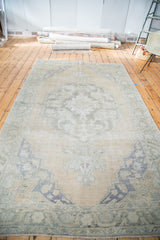 Distressed Oushak rug corner showing faded royal blue spandrel, peach field, and muted border.