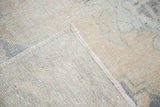 Close-up of distressed Oushak carpet, showing faded peach pile and tight hand knotting.
