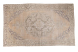 Distressed Oushak carpet showcasing a peach field, faded royal blue spandrels, and central medallion.