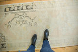 Distressed Oushak runner with faded ivory, peach, charcoal, and saffron geometric patterns underfoot.