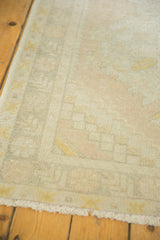 Distressed vintage Turkish Oushak runner with faded ivory, peach, and yellow geometric patterns.