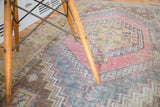 Faded cinnabar, grey, and brown geometric patterns on a distressed Oushak rug.