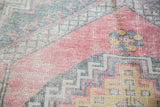 Distressed Turkish Oushak rug featuring faded cinnabar red and geometric stepped patterns.