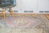 Faded cinnabar red and gold geometric medallion on distressed Turkish Oushak rug.