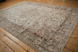 Angled detail of a distressed Oushak rug, showing light rose spandrel, floral patterns, and cloudband borders.