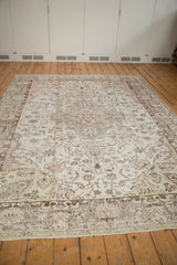 Distressed Oushak carpet with faded ivory, light rose, and charcoal floral patterns.