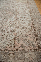Angled view of distressed Oushak carpet showing faded ivory, light rose, and charcoal ornate patterns.