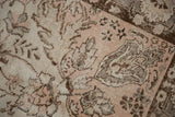 Distressed Oushak carpet texture with faded rose, ivory, and grey curvilinear motifs.