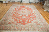 Distressed Oushak carpet with faded cranberry field and dark grey floral border.