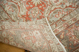 Rolled edge of distressed Oushak carpet showing hand-knotted reverse and faded cranberry, grey pile.