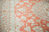 Textured view of distressed Oushak carpet, faded cranberry field, grey motifs, dark border.