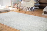 Distressed vintage Oushak carpet showcasing a faded ivory curvilinear medallion and subtle leaf patterns.