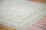 Distressed Oushak rug with soft faded green border and charcoal outlined floral patterns.
