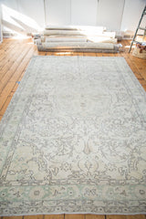 Distressed vintage Oushak carpet; faded ivory, beige, oxidized green, and charcoal floral motifs.