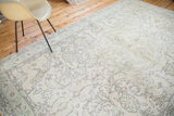 Distressed Oushak rug with faded ivory field, expressive charcoal leaves, scalloped medallion.