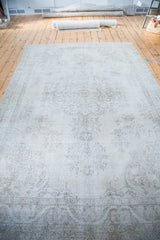 Subtle curvilinear patterns in charcoal and pastel hues on the vintage Oushak carpet.