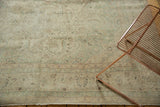 Faded celadon green, bronze, and ivory curvilinear floral design on a vintage Oushak rug.