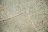 Faded celadon floral pile of a vintage Oushak, revealing its tightly woven beige foundation.