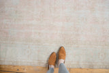 Distressed Oushak carpet showcasing faded blush rose, ivory, and blanched grey floral motifs.