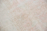 Distressed texture and faded floral pattern in blush rose, ivory, and light grey Oushak.