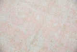Distressed Oushak carpet texture with faded blush rose, ivory, and grey floral patterns.