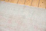 Distressed Oushak pile with blush rose, ivory, and blanched grey floral motifs.