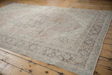 Distressed Oushak corner with faded blush and sea foam floral motifs, charcoal border.