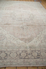 Distressed Oushak carpet with faded dusty blush, sea foam, and charcoal floral patterns.