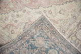 Distressed Oushak rug corner, revealing faded blush pile and tightly woven blue-brown foundation.