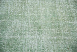 Distressed faded green pile texture of a vintage hand-knotted Oushak rug.