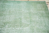 Close-up of the faded green distressed surface of the vintage Turkish Oushak rug.