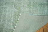 Distressed faded green pile of a vintage hand knotted Oushak carpet, revealing its woven foundation.