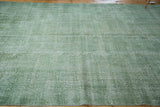 Textural detail of a distressed faded green Oushak rug with fringe.