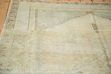 Distressed vintage Oushak carpet showcasing abrashes, soft earth tones, and dark geometric outlines.