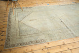 Distressed Oushak carpet corner with faded beige abrashes and coffee-brown geometric borders.