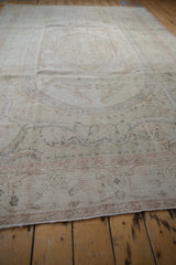 Faded blush rose and ivory Aubusson-style motifs on distressed Oushak rug pile.