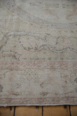 Distressed hand-knotted Oushak rug pile showing muted curvilinear patterns in antique ivory and dusty blush.