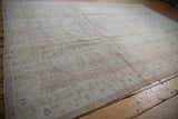 Vintage Oushak rug with a distressed ivory pile and faded blush rose border.