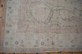 Distressed Oushak rug corner showing antique ivory, dusty blush rose, and subtle blue outlines.