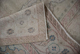 Distressed Oushak rug with soft blush and ivory pile, showcasing its hand-knotted foundation.
