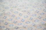 Textured pile of distressed Oushak rug, featuring faded blue repeating motifs and apricot abrashes.