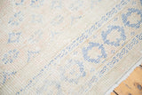 Distressed Oushak rug close-up with faded apricot, beige, royal blue patterns, and fringe.