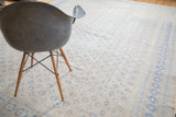 Distressed vintage Oushak carpet with faded blue motifs on an apricot beige field.