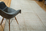 Distressed Oushak rug with faded allover floral design in soft beige tones.