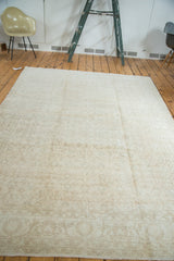Subtle floral pattern and distressed texture of a light beige Oushak rug's border.