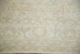Distressed Oushak rug's subtle floral pattern in soft tan and ivory tones.