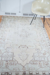 Distressed Oushak rug with faded minimalist medallion and subtle ivory, beige patterns.