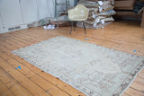 Distressed hand-knotted Oushak rug with minimalist oblong medallion, faded ivory, beige, and seafoam.